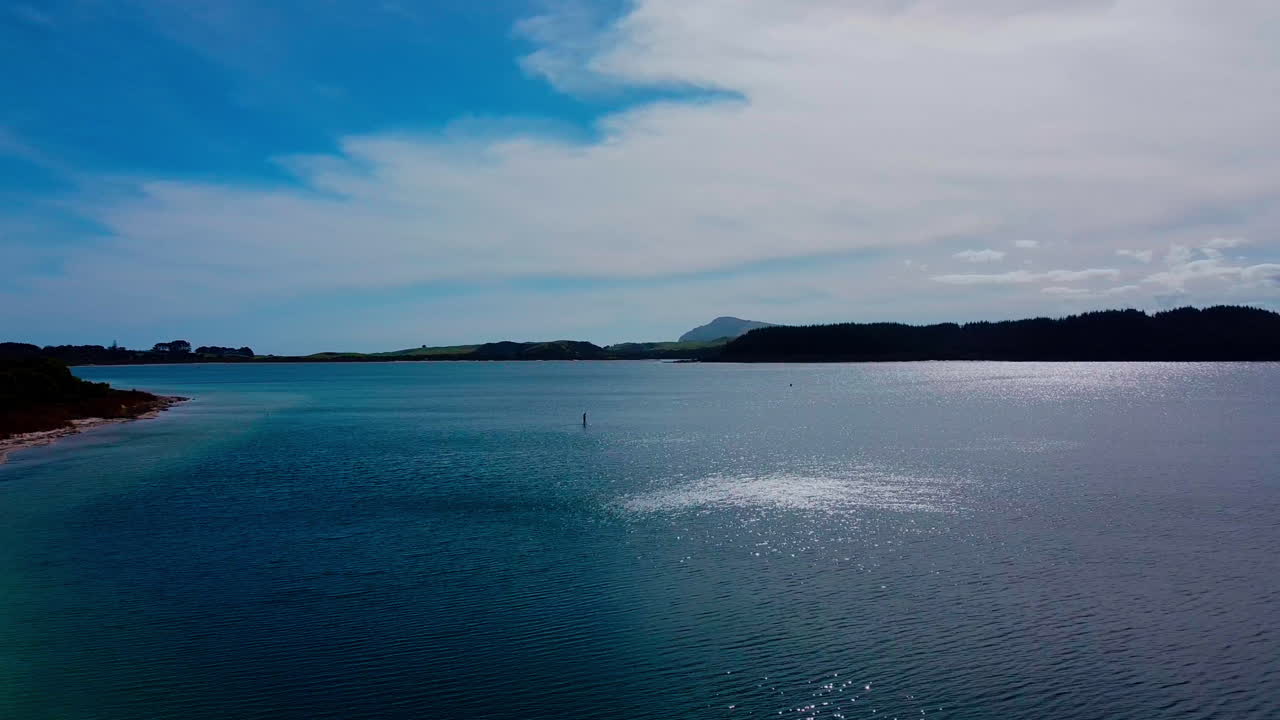 Drone shot moving toward paddle boarder on a lake at Kai Iwi Lake, New Zealand
