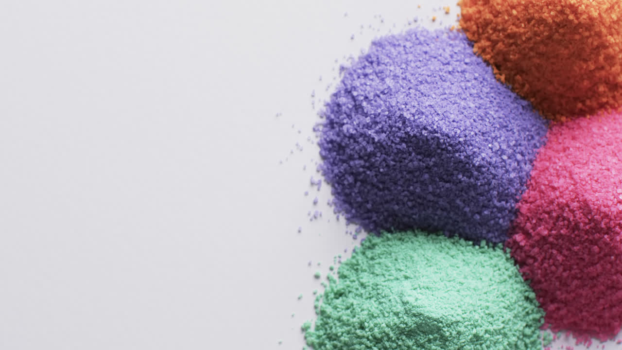 video de un primer plano de montones de granos de arena multicolores y espacio de copia sobre un fondo blanco