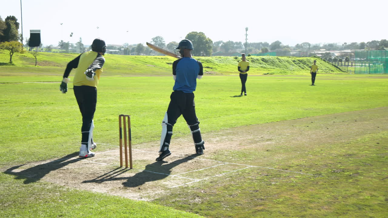 Cricket players in action on sunny field, bowler delivering fast ball