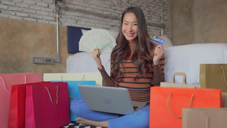 young asian girl holds a credit card and takes cash choosing between them nods approvingly