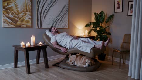 man relaxing in a spa chair with his dog
