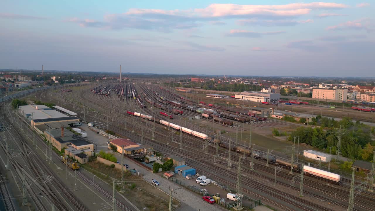 Aerial view of a vast railway yard with numerous tracks and trains under a cloudy sky. Amazing flight panorama overview drone