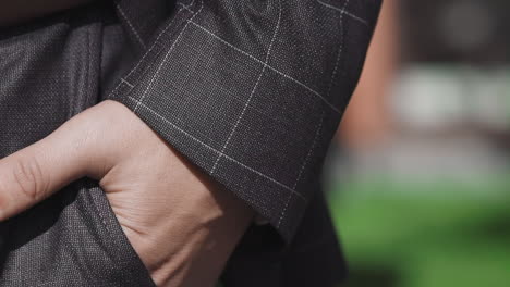 businessman puts hand into pocket walking along city street