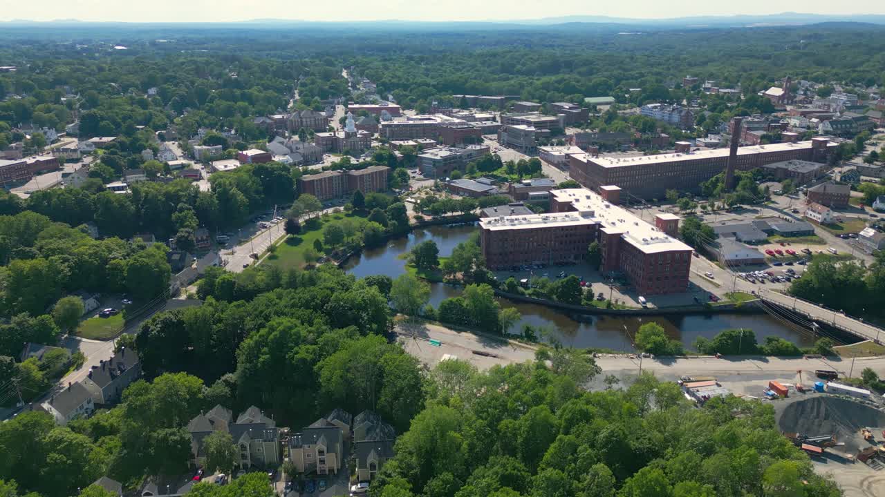 Volo di drone alto e lento sopra il centro storico di Dover, NH, USA. Presenta il vecchio mulino, il fiume, il Municipio. Vola in avanti, poi gira e si inclina verso il basso per rimanere sul mulino.