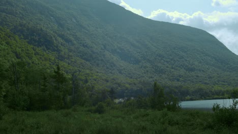 Montañas-Verdes-Se-Inclinan-Hacia-Un-Lago-En-Calma-Mientras-La-Cámara-Gira