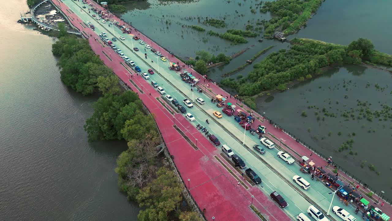 Vibrant aerial drone view of a riverside road in the Philippines with cars, food stalls, and mangroves. Perfect for travel, culture, lifestyle, and urban development projects