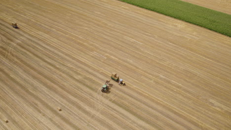 tractor in a farm field carries bales of hay and stacks them on hay carrier aerial