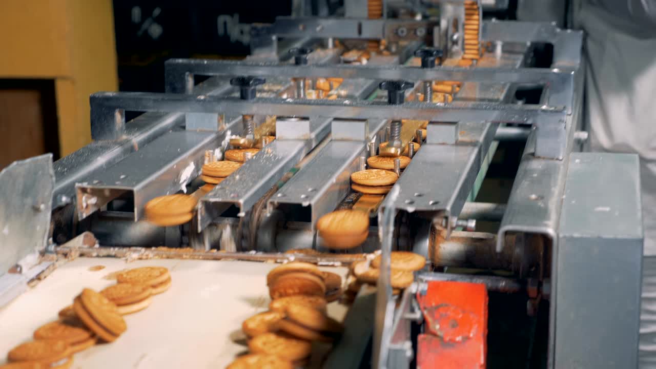 las galletas van a lo largo del transportador y luego se dejan caer a otra cinta. 4k.