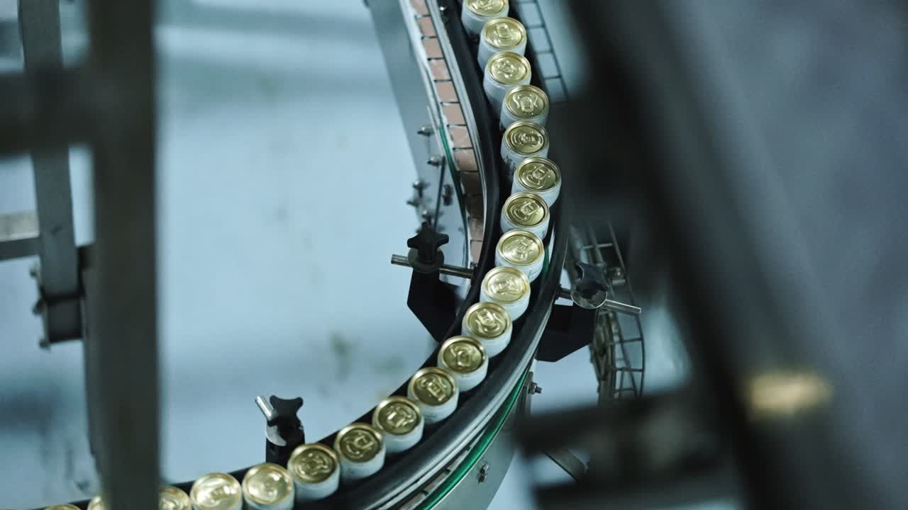 White and gold cans running through a conveyor system in a factory
