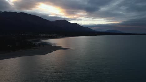 Kluane-Lake-silhouetted-during-colorful-sunset-in-winter,-aerial-drone