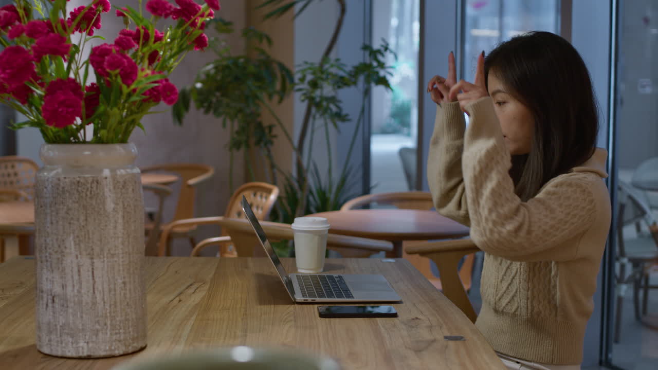 若いアジア人美しい中国人女の子がオンラインで電話をして手でジェスチャーをしています