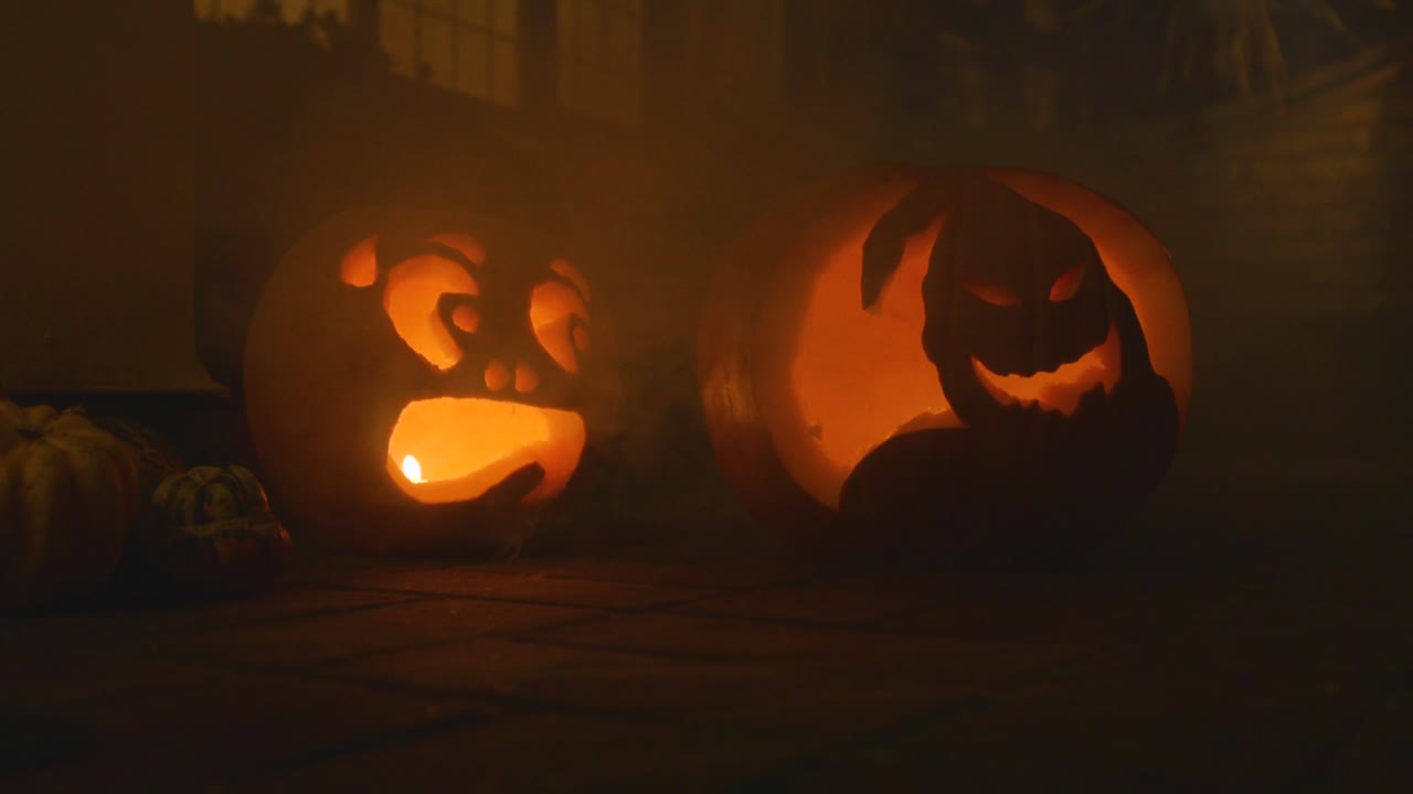 2 carved lit pumpkin outside the front of a house Halloween with smoke