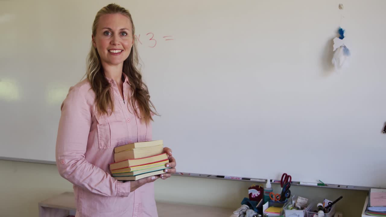 maestra que sostiene una pila de libros en la escuela