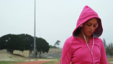 vista frontal de una joven atleta caucásica escuchando música en un recinto deportivo 4k