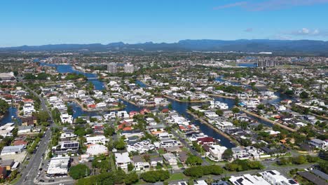 aerial footage of gold coast suburbs, showcasing residential areas, waterways, and distant mountains under clear blue skies