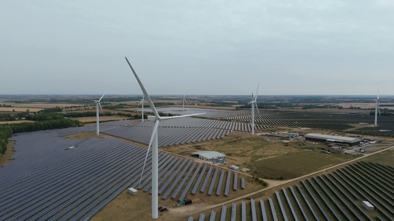 Aerial drone shot of sustainable power generation with solar panels and wind turbines at sunset in Wellingborough United Kingdom