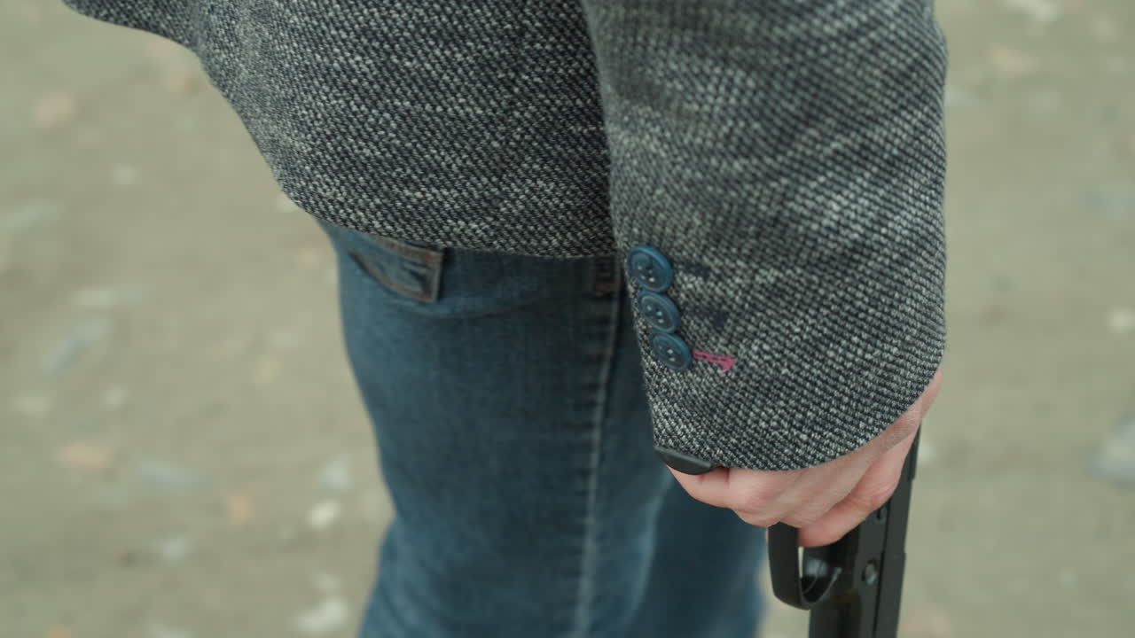 회색 재, 검은 캔버스 및 파란 청바지를 입은 사람이 길을 고, 에 권총을 들고 있는 근접한 모습