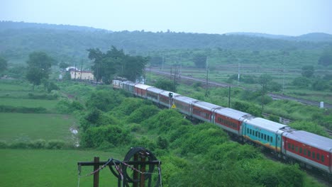 indian railways passenger train passing through green hills in north central india