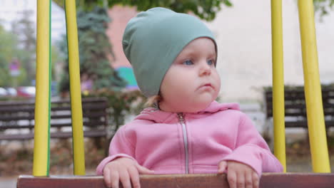 head on close up view of toddler swinging on swing in city park