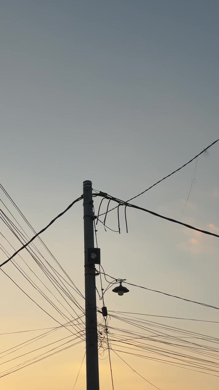 Utility Pole with Tangled Power Lines Against Sunset Sky