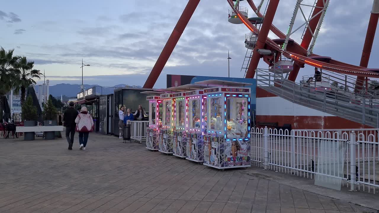 Ferris wheel and arcade machines outdoors with palm trees