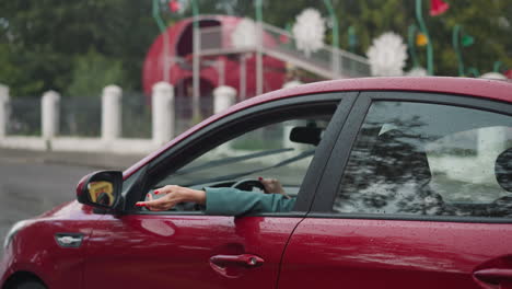 covered with raindrops red car moves past amusement park