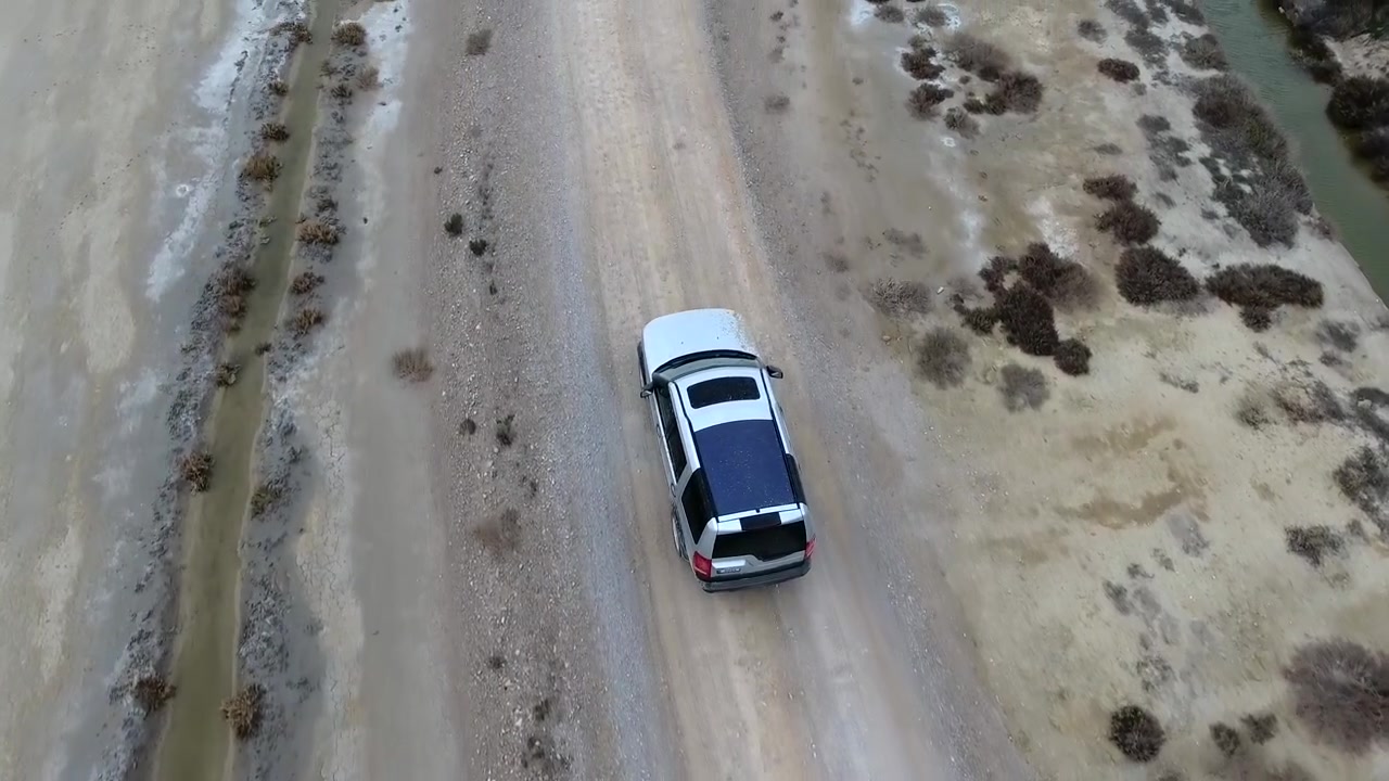 Bataklık Arazideki Toprak Yolda İlerleyen Beyaz SUV'nin Kuşbakışı Görünümü