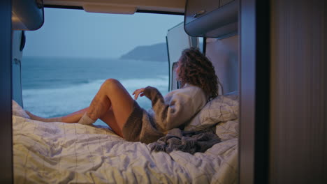 lady relaxing cozy motorhome looking gloomy evening seascape. calm woman lying