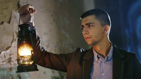 scared young man in a dark hallway holding an oil lamp in his hand dressed in a suit