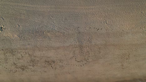 vista aérea de arriba hacia abajo de sombrillas de playa cerca de las olas en una playa de arena en el algarve, portugal