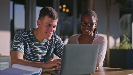 students collaborate on a laptop outside