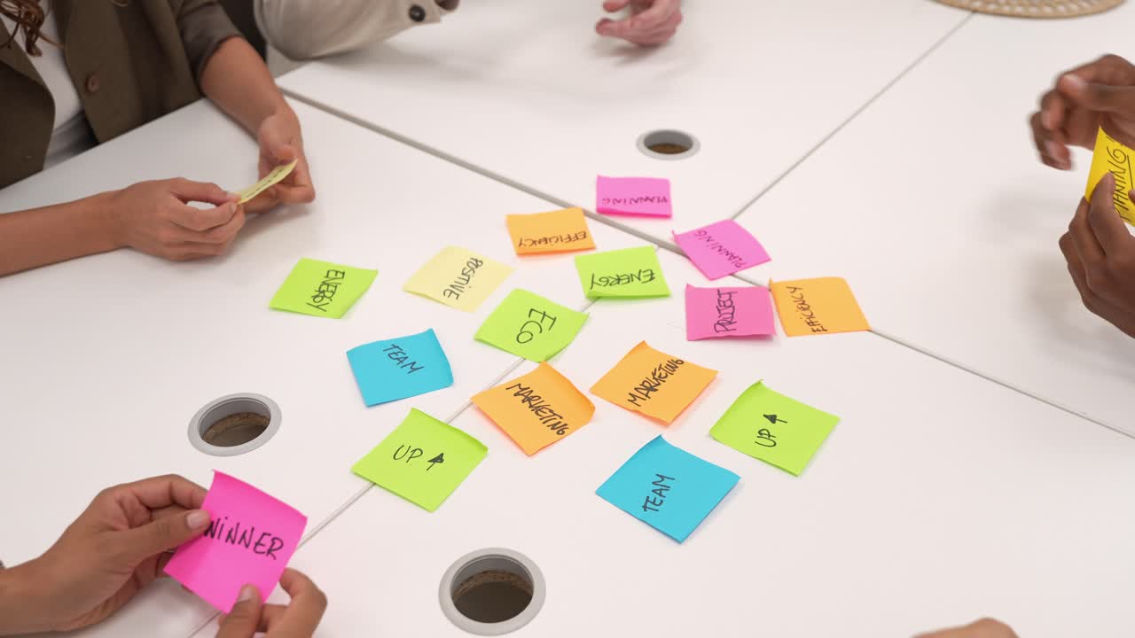 Equipo de negocios haciendo una lluvia de ideas con notas adhesivas de colores sobre una mesa blanca