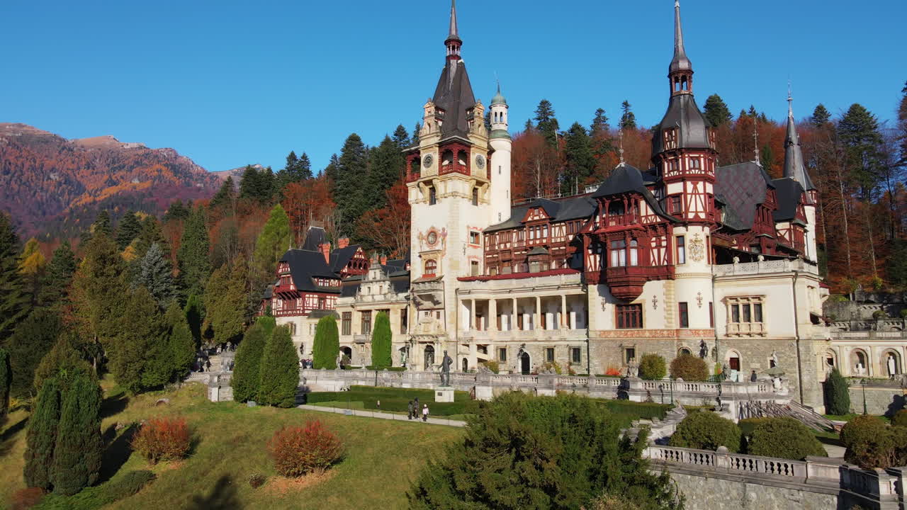 Aerial drone view of The Peles Castle in Romania. Castle with gardens in Carpathians, forest around it, tourists