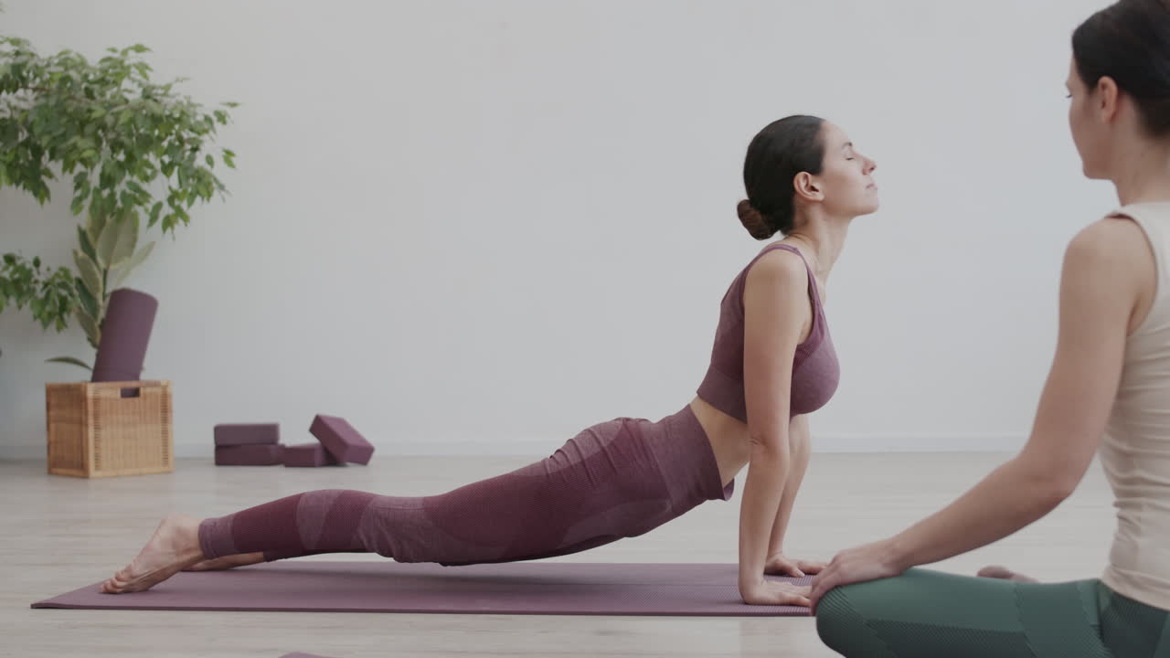 entrenador de yoga observando a una mujer haciendo ejercicios de yoga