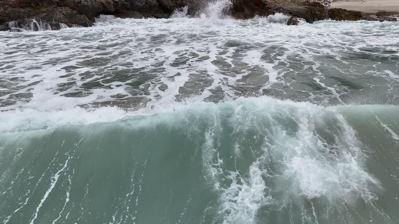 Filmato di potenti onde oceaniche che si infrangono su pietre nere, catturando la schiuma delle onde, gli schizzi d'acqua e il movimento costiero energico per progetti cinematografici o naturalistici.
