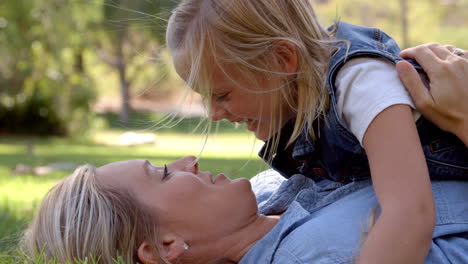 young daughter lying on her mother in a park, close up