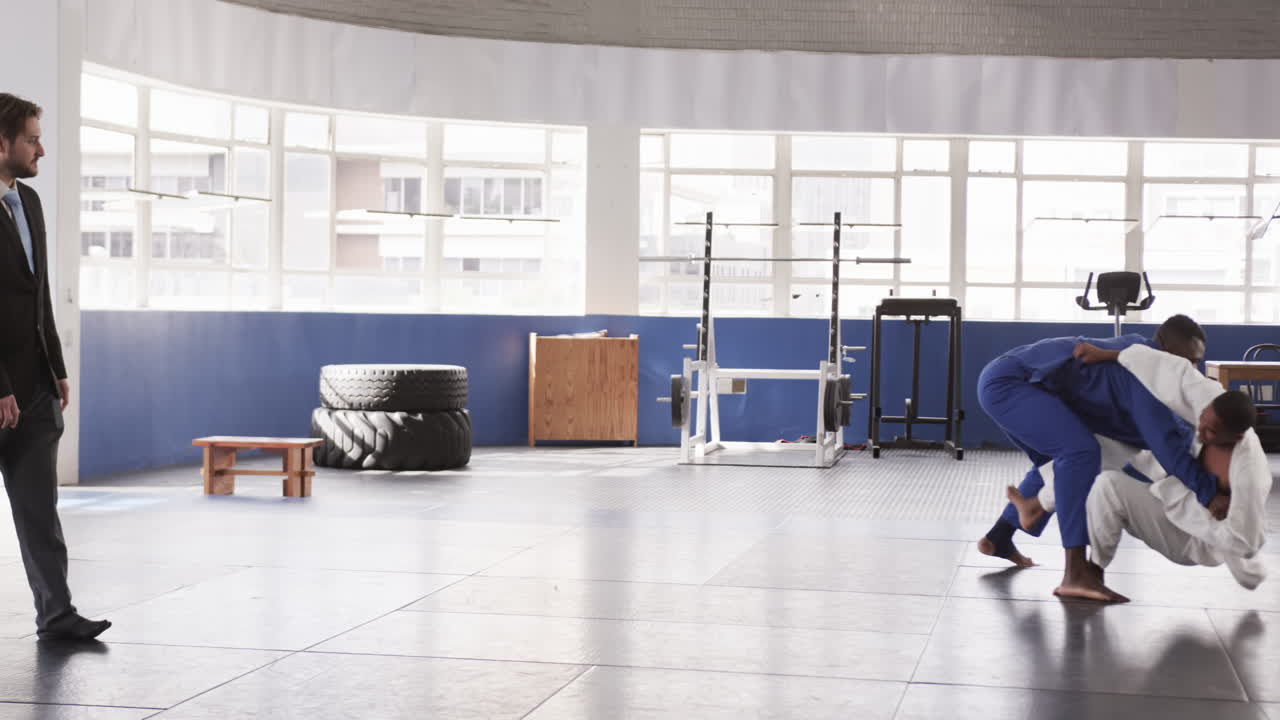 Athletes practicing judo techniques in gym, demonstrating strength and agility