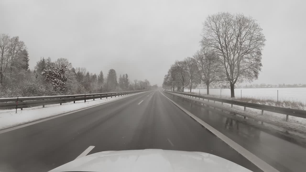 떨어지는 눈송이와 운전하는 자동차 앞 창문에서 빠르게 녹고, 겨울에는 눈 덮인 나무가 있는 고속도로에서 빠르게 운전하세요