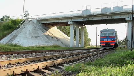 electric train moving on railroad under car bridge. modern train on rail way