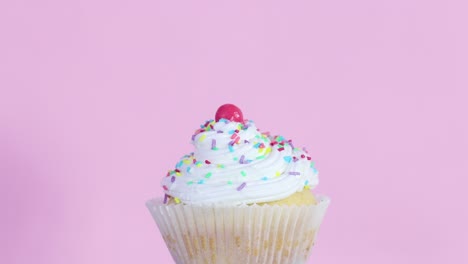 slowly rotating one cup cake with cream on pink theme
