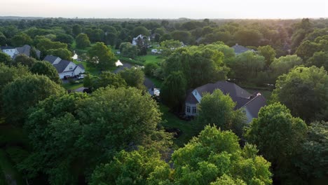 quiet sunrise in well-maintained suburb district of town. river flowing between single family houses and one family homes in america. aerial orbit wide shot. green trees in summer season