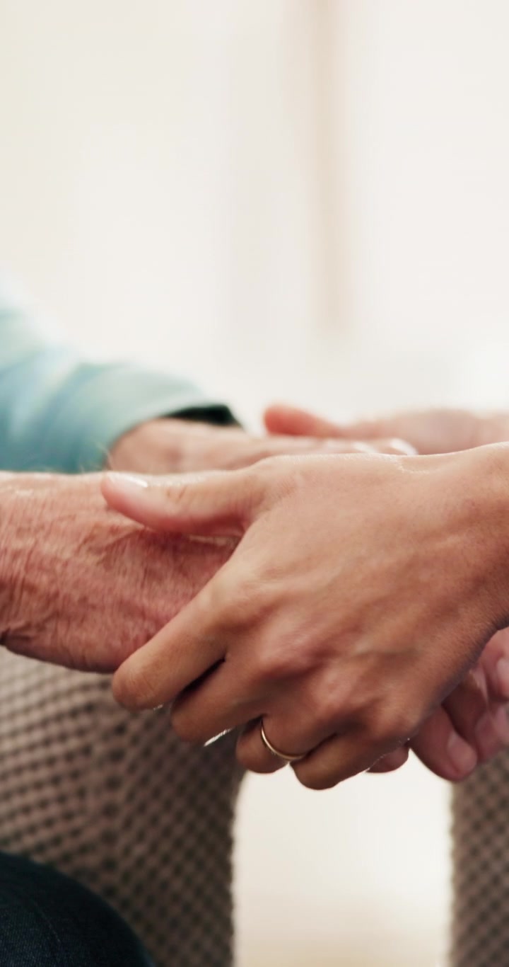 Giovane donna che conforta un uomo anziano tenendogli le mani