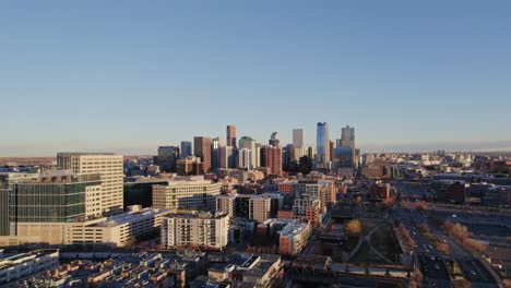 drone aerial view of denver colorado skyline flying back passing the confluence modern apartment complex high rise building during golden hour sunset