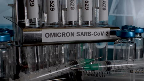 omicron sample test tubes being removed from rack next to empty vial bottles and syringes. static, close up