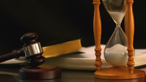 sand flowing through hourglass beside gavel and bible