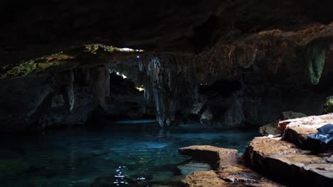 tilt up shot of a beautiful underground mexican cenote with stalactites growing from the roof and crystal clear blue fresh water in a eco-park kantun chi on playa del carmen in riviera maya, mexico