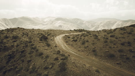 winding dirt road through the pamir mountains in tajikistan under cloudy skies
