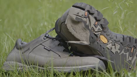 worn and used hiking shoes lying in a grass field