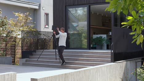 Un-Hombre-Está-Escaneando-Cuidadosamente-El-Exterior-De-Una-Casa-Con-Un-Dispositivo-Matterport,-Capturando-Imágenes-Detalladas-En-3D-Para-Un-Recorrido-Virtual-Para-Compradores-Potenciales