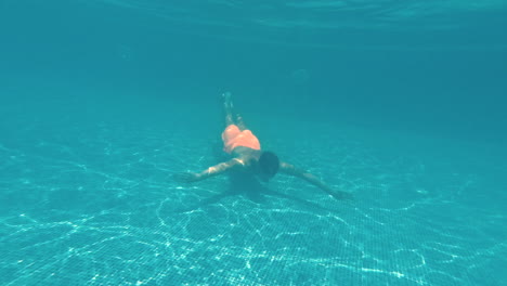un joven nada bajo el agua en una piscina.